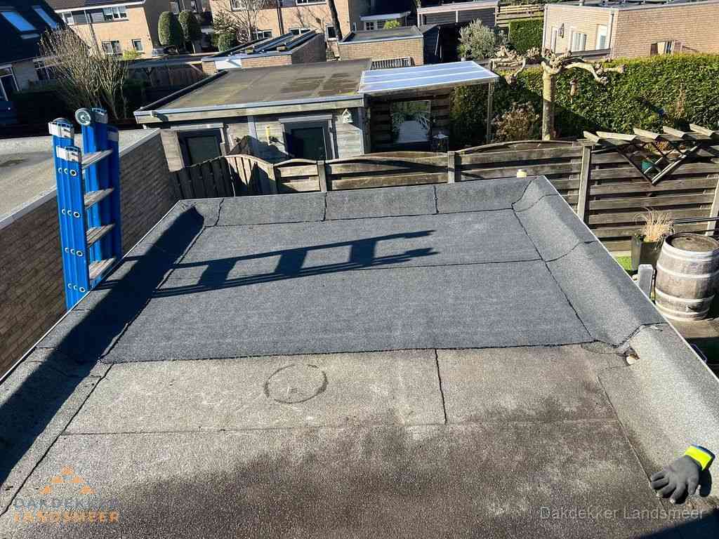 Dakdekker legt onderlaag op plat dak met houten constructie in Landsmeer