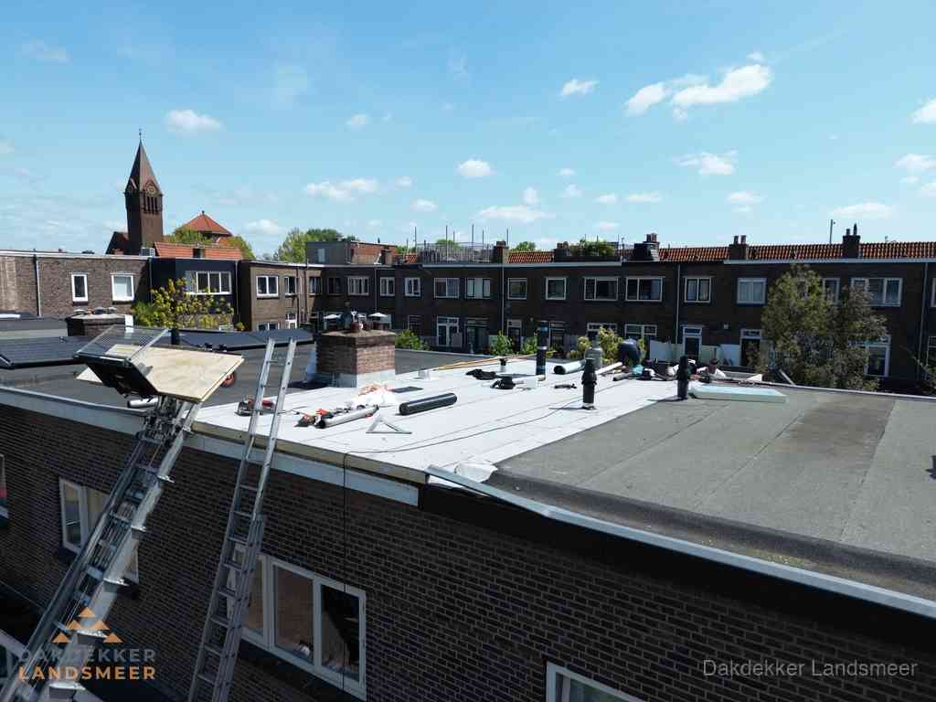 Dakdekkers aan het werk op plat dak in Landsmeer