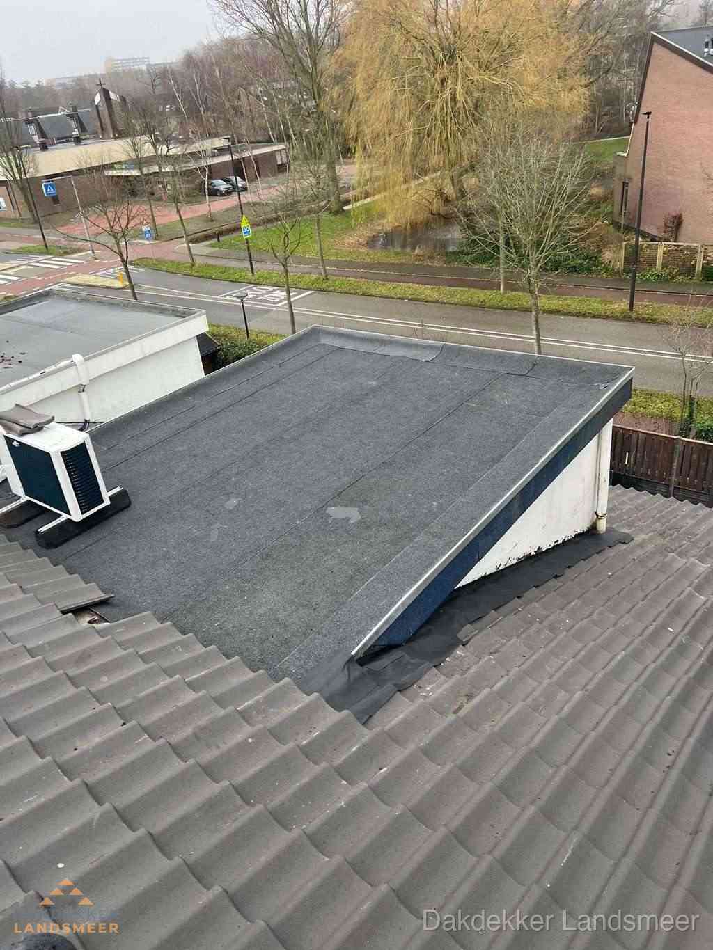 Plat dak met bitumen dakbedekking naast schuin pannendak in Landsmeer