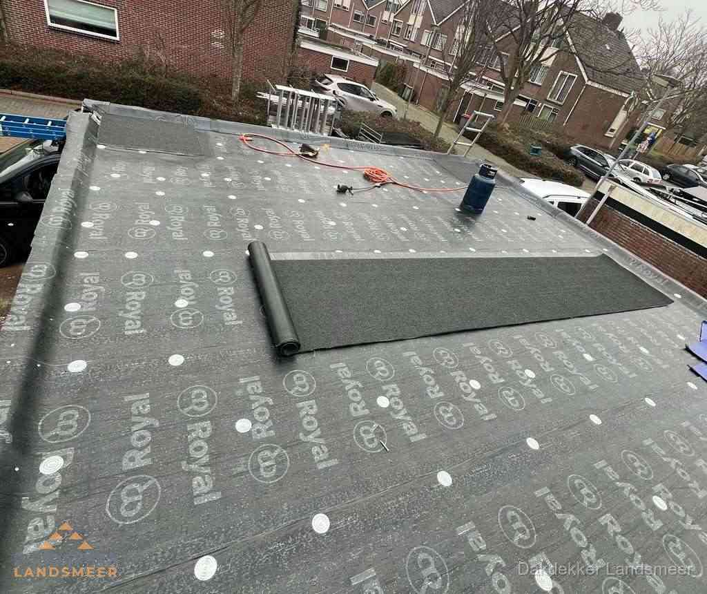 Dakdekker aan het werk met gasbrander op plat bitumen dak in Landsmeer